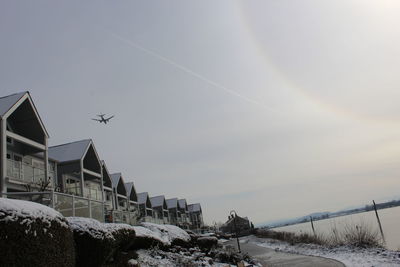 Low angle view of airplane flying over snow covered landscape