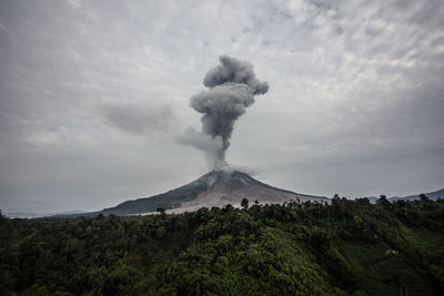 Scenic view of smoke emitting from volcanic crater against sky