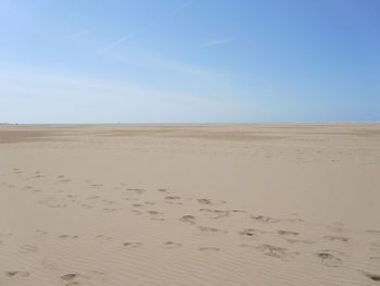 Scenic view of sand dunes against clear blue sky