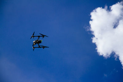 Low angle view of drone flying against blue sky during sunny day