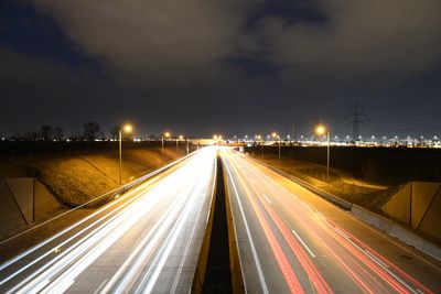 Light trails on road in city against sky at night