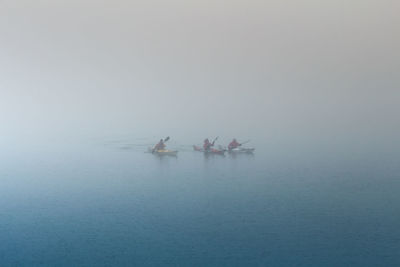 People rowing in lake during foggy weather