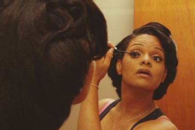 Close-up of a woman applying mascara in mirror