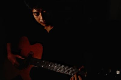 Portrait of young woman playing guitar