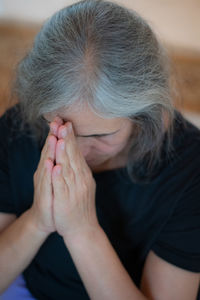 Senior woman with eyes closed praying at home