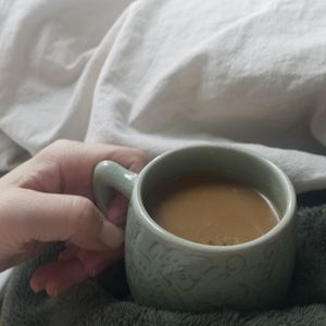 Midsection of man drinking coffee cup on bed