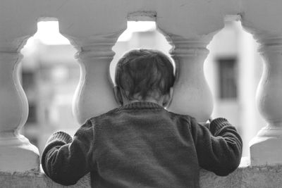 Rear view of boy standing by balustrade 