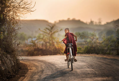 Man riding bicycle on road against sky