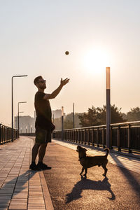 Young man is playing with his dog on empty street in the morning.