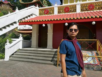 Portrait of smiling young woman standing against built structure