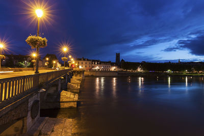 Illuminated bridge over river against sky at night