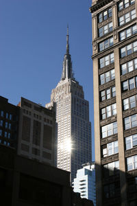 Low angle view of tall buildings against clear blue sky