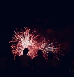 Silhouette people watching firework display at night