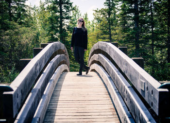 Man standing on footbridge in forest