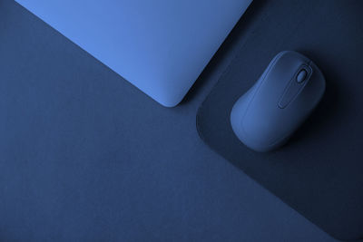 Directly above shot of laptop with mouse over blue background