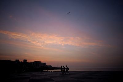 Silhouette of people at beach during sunset