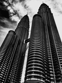 Low angle view of skyscrapers against cloudy sky