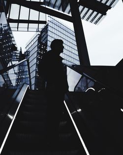 Silhouette of man standing on escalator