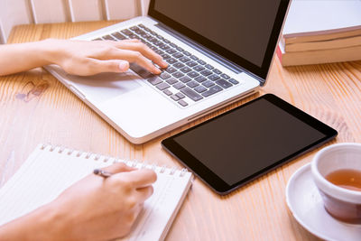 Midsection of woman using laptop on table