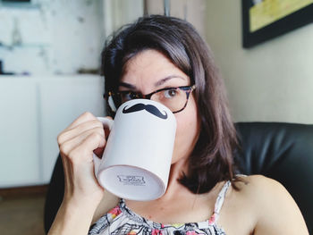 Portrait of young woman drinking  at home