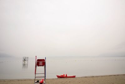 Lifeguard chair at beach against sky during foggy weather