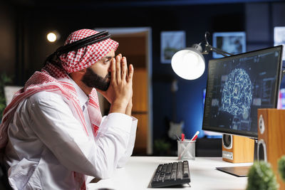 Young man using phone while working at desk in office