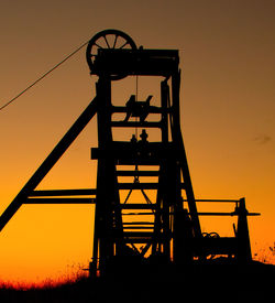 Low angle view of silhouette cranes against sky during sunset