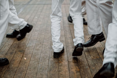 Low section of men walking on floorboard