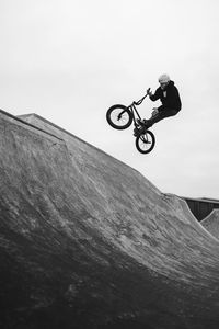 Low angle view of man jumping bicycle against sky