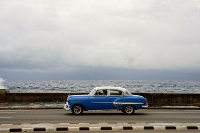 Vintage car on beach against sky