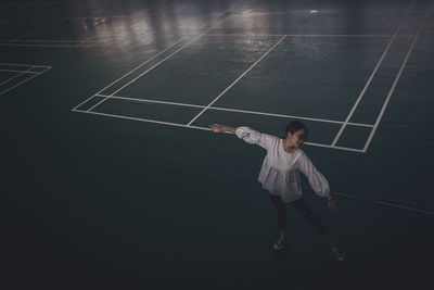 High angle view of young woman dancing on court at night