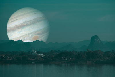 Scenic view of lake and mountains against sky at night