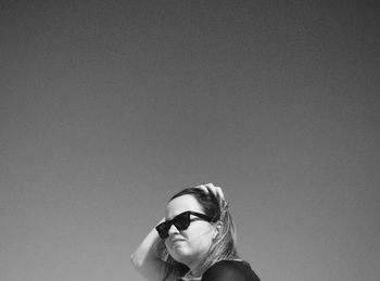 Portrait of young woman wearing sunglasses against white background