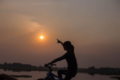 Silhouette man standing by sea against sky during sunset