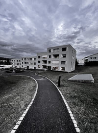 Empty road amidst buildings against sky in city