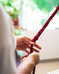 Close-up of hand weaving macramé hanging planter.