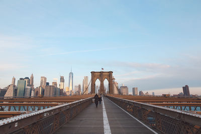 People walking on brooklyn bridge against sky in city