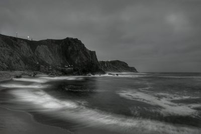 Scenic view of mountain at beach against cloudy sky