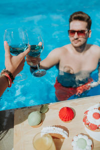 Young beautiful couple eating cookies by the pool