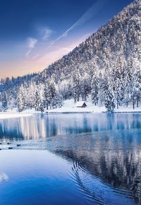 Scenic view of lake by snowcapped mountains against sky during winter