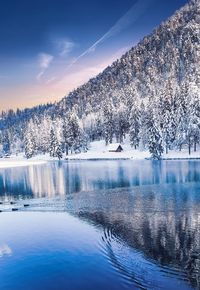Scenic view of lake by snowcapped mountains against sky during winter