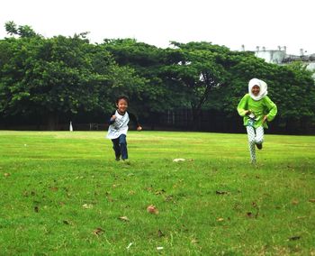 Full length of siblings running on field