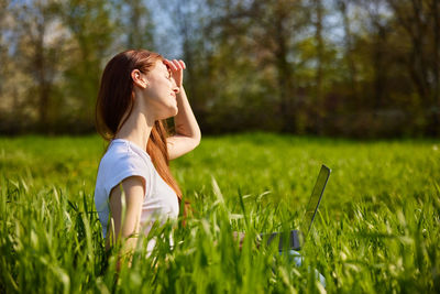 Side view of young woman standing on grassy field