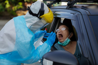 Doctor or nurse wearing ppe n95 mask face shield and personal car road screening for covid-19 virus