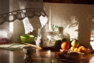 Variety of fruits with teapot and cup on table in kitchen