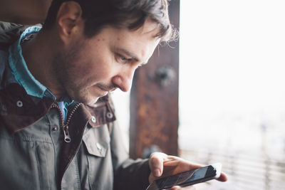 Serious man using phone against clear sky