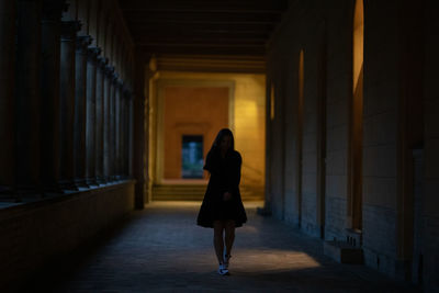 Rear view of woman walking in corridor of building