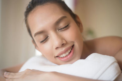 Close-up of smiling young woman lying on massage table in spa