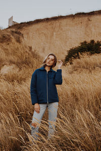 Young woman standing by plants against sky