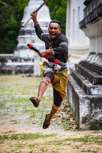 Full length of warrior jumping against old building